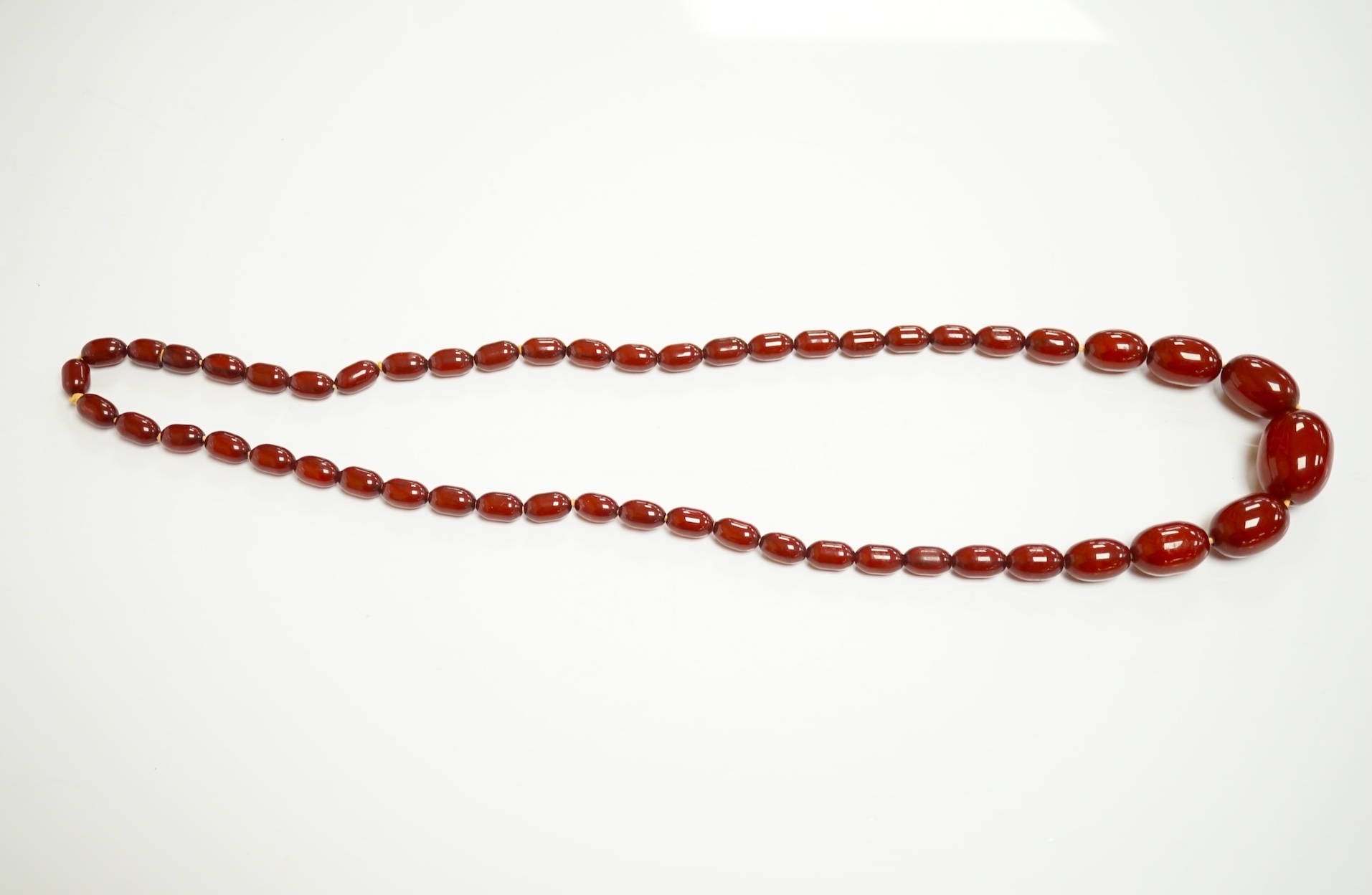 A single strand graduated simulated cherry amber oval bead necklace, 70cm, gross weight 51 grams. Condition - fair to good